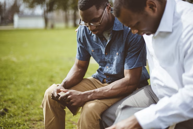 african-american-male-friends-sitting-praying-with-closed-eyes-bible-their-hands