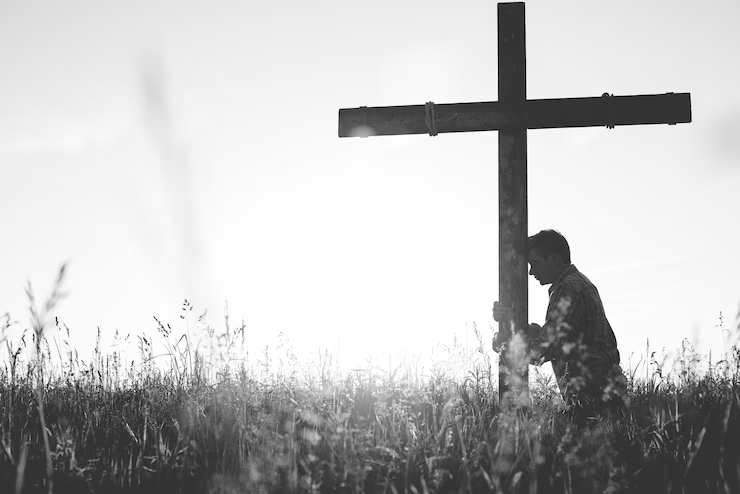 man-praying kneeling at cross