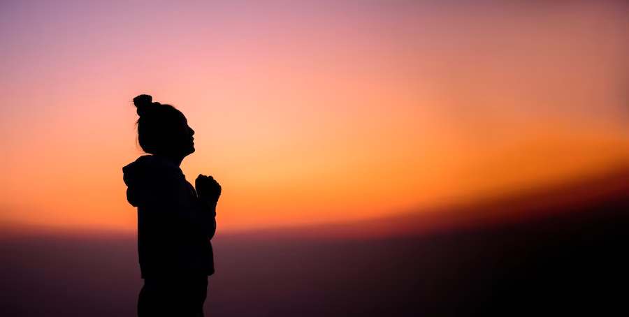 woman praying in faith  at sunset 